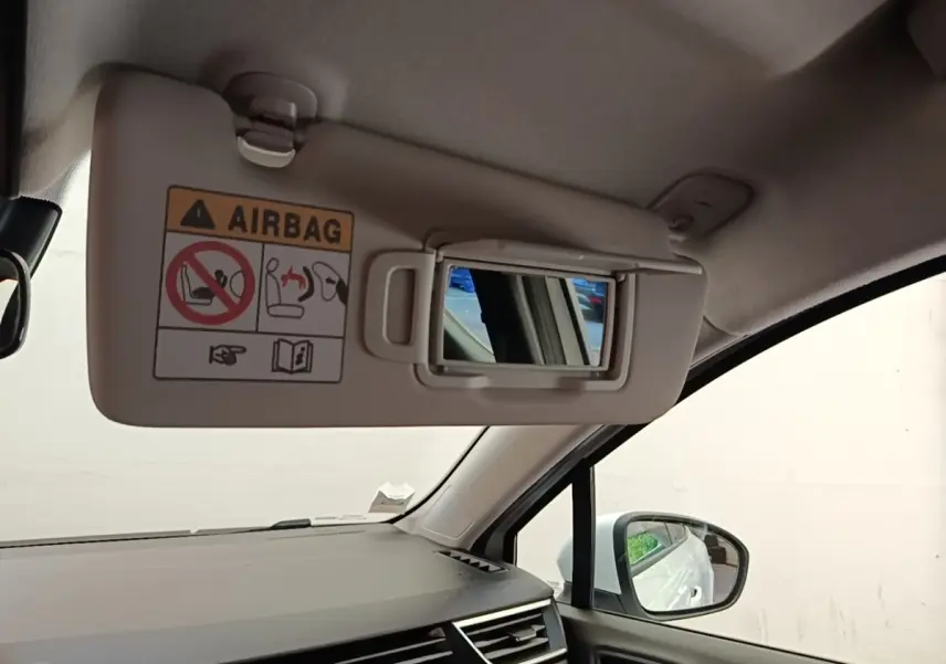 Intérieur Renault Clio blanc, vue côté passager avec pare-soleil relevé et miroir de courtoisie visible.