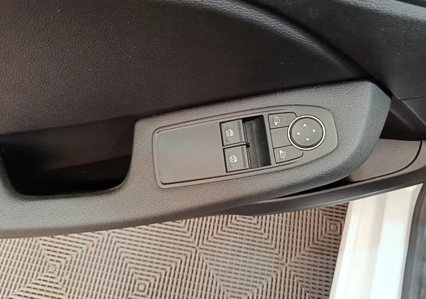 Gros plan sur la commande des vitres électriques côté conducteur de la Renault Clio Business E-TECH blanche, porte ouverte.