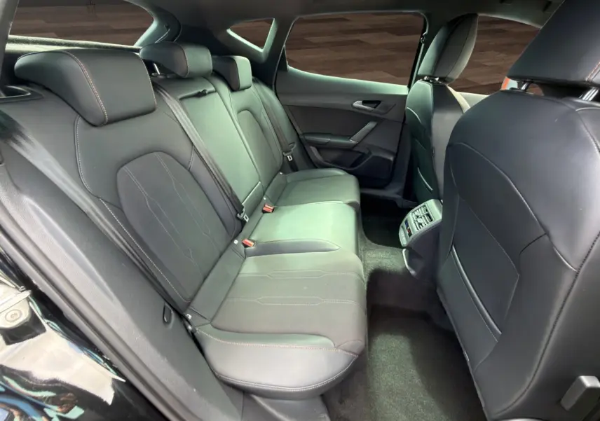 Vue intérieure arrière du CUPRA Formentor 2025 montrant les sièges noirs en cuir et tissu avec surpiqûres contrastantes.
