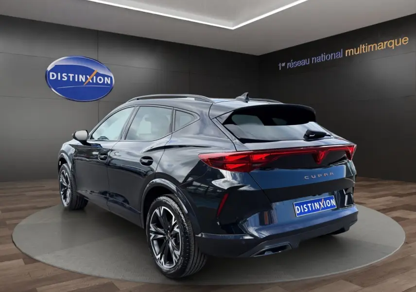 Vue 3/4 arrière droite d'un CUPRA Formentor bleu foncé avec feux arrière LED et jantes noires en alliage.