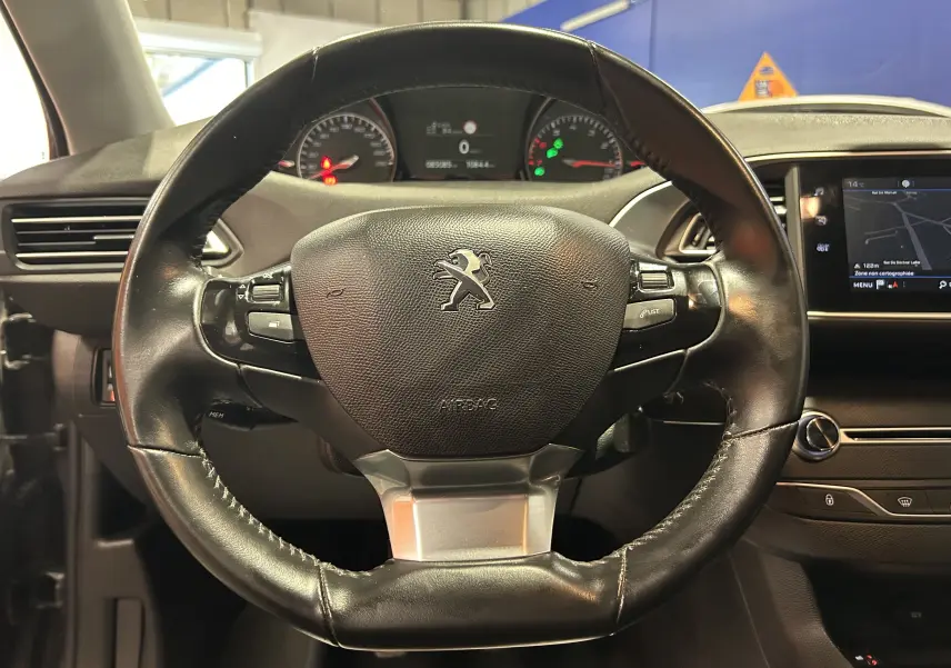 Gros plan sur le volant en cuir noir de la Peugeot 308 Active Pack 2021, avec tableau de bord et écran tactile visibles.