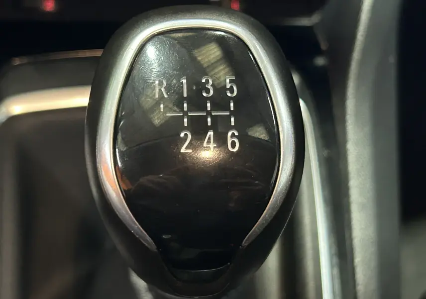 Gros plan sur le levier de vitesse noir brillant d'une Peugeot 308 Active Pack gris, boîte manuelle 6 rapports.