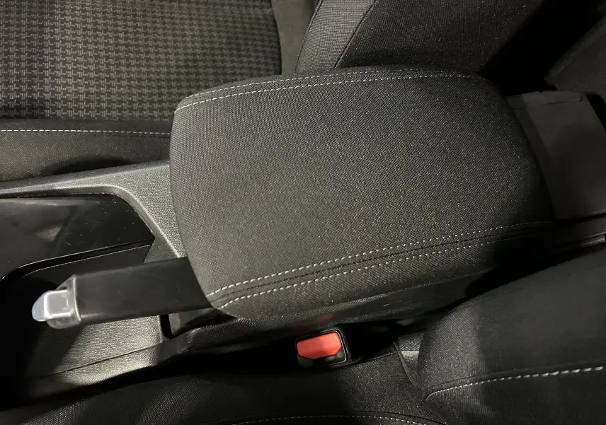 Gros plan sur l'accoudoir central et frein à main manuel d'une Peugeot 308 Active Pack gris, intérieur tissu noir.