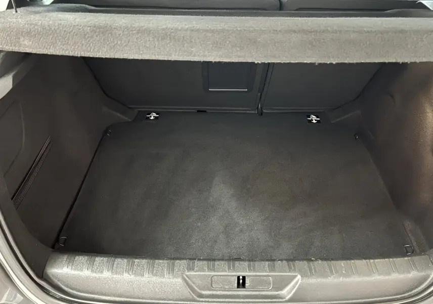 Coffre ouvert d'une Peugeot 308 Active Pack gris 2021, vue de l'arrière montrant un espace de rangement propre et spacieux.