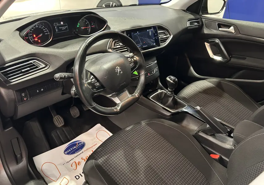 Vue intérieure côté conducteur de la Peugeot 308 Active Pack 2021 avec tableau de bord noir et volant cuir.