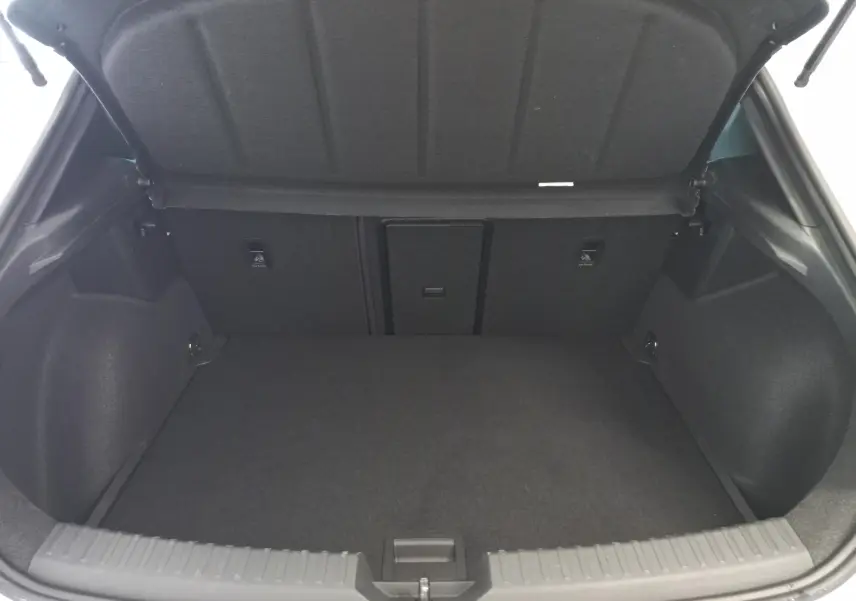 Coffre ouvert d'une CUPRA Leon Phase 2 1.5 eTSI 150 DSG7 V, intérieur spacieux et revêtement gris foncé.