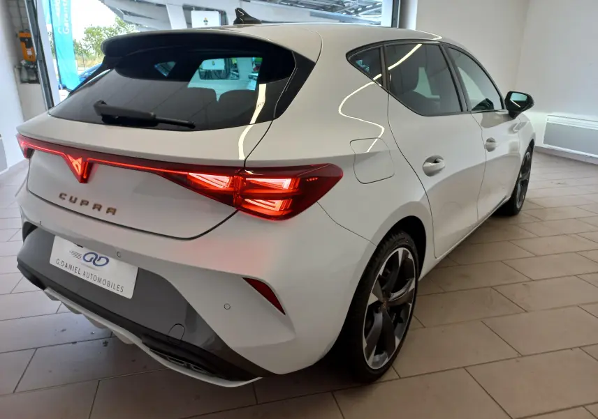 Vue 3/4 arrière droite de la CUPRA Leon blanche Nevada 2025 avec feux arrière LED et jantes noires distinctives.