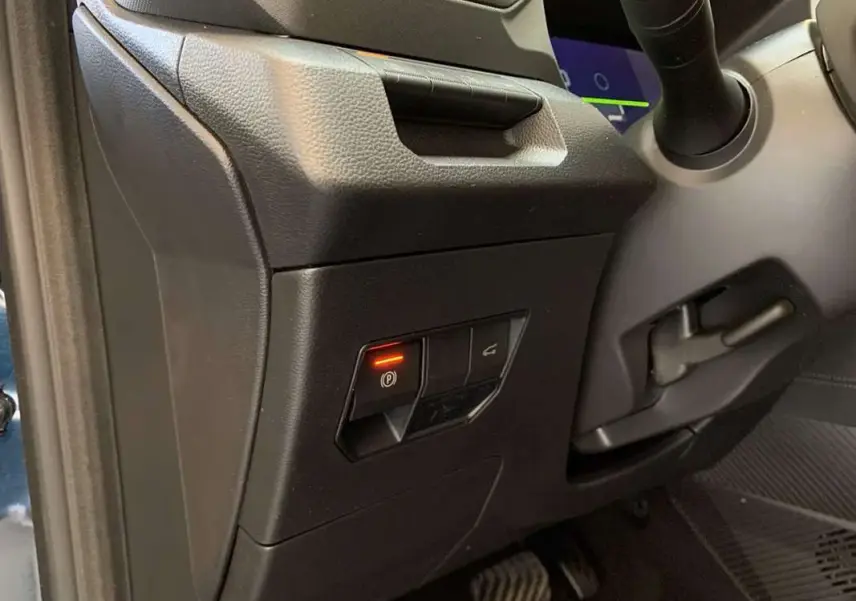 Détail intérieur du tableau de bord côté gauche du Dacia Bigster Hybrid 155 Journey Plus avec bouton frein à main électrique allumé.