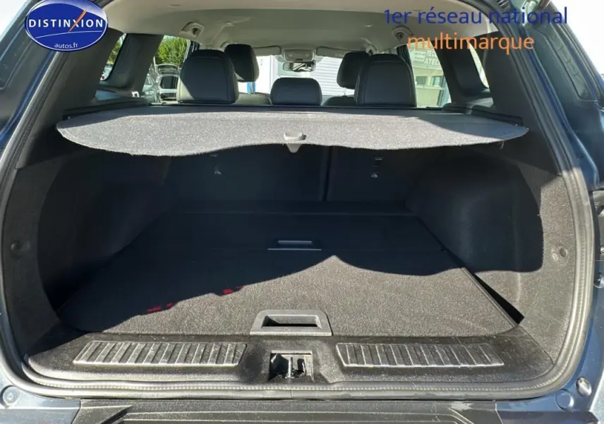 Coffre ouvert vu de l'arrière d'un Renault Kadjar gris foncé avec cache-bagages et sièges arrière noirs visibles.