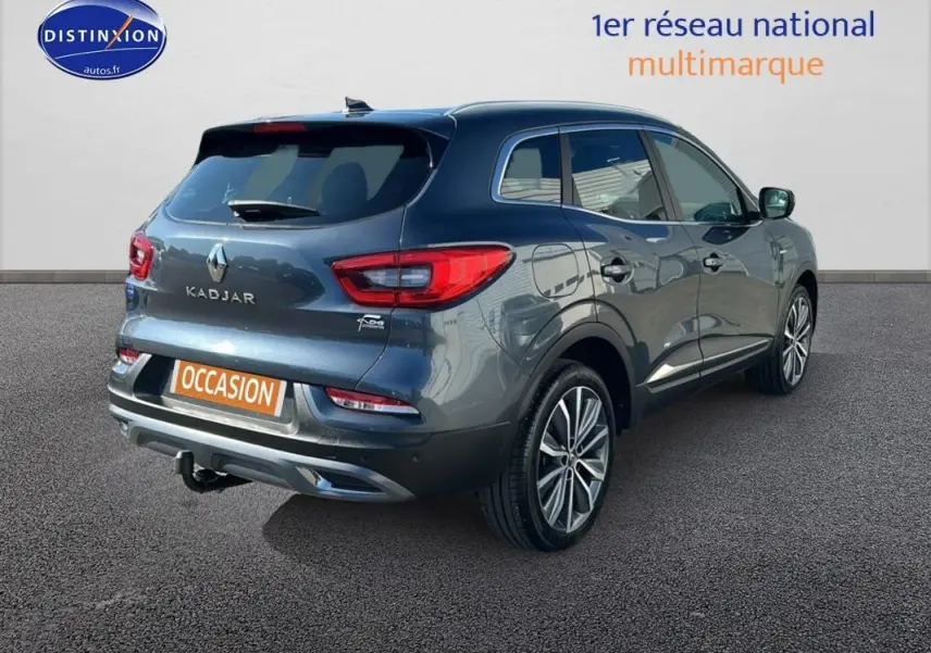 Vue 3/4 arrière droite d'un Renault Kadjar gris foncé avec jantes alliage 19 pouces et barres de toit.