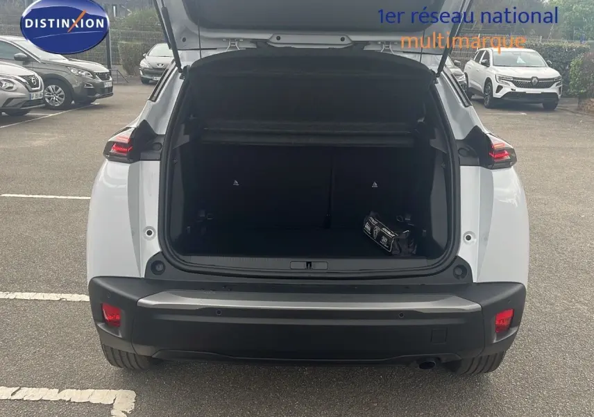 Vue arrière d'un Peugeot 2008 blanc Okenite Metal avec coffre ouvert montrant un kit de sécurité à l'intérieur.