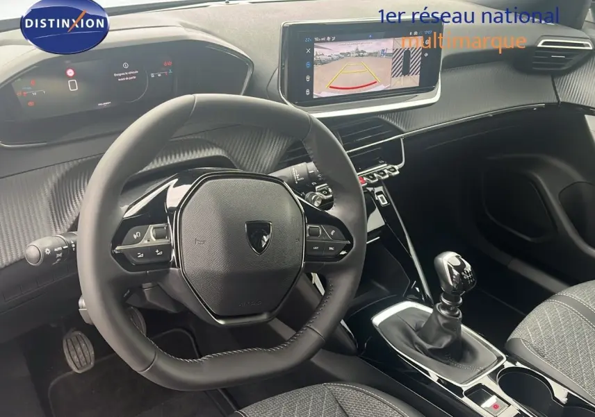 Intérieur de la Peugeot 2008 2025, vue du poste de conduite avec volant, écran tactile et levier de vitesse manuel.