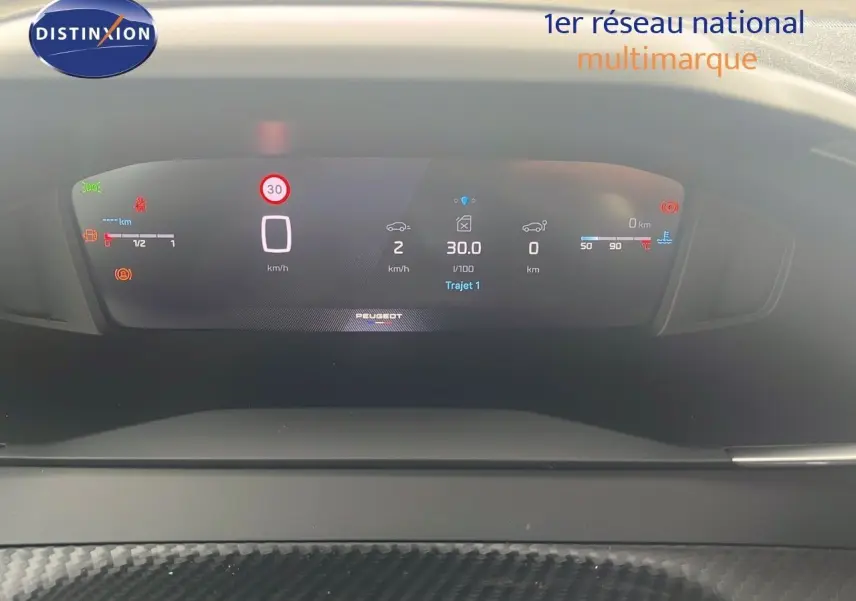 Affichage numérique du tableau de bord du Peugeot 2008 blanc, montrant la vitesse, consommation et indicateurs divers.