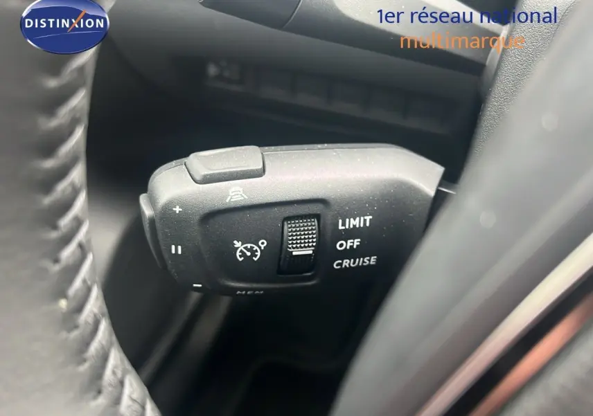 Gros plan sur la commande de régulateur de vitesse à gauche du volant d'une Peugeot 2008 blanc Okenite métal 2025.