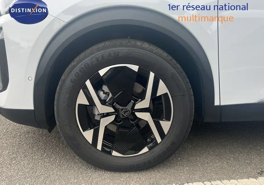 Gros plan sur la roue avant gauche d'un Peugeot 2008 blanc Okenite avec jante alliage noire et argentée.