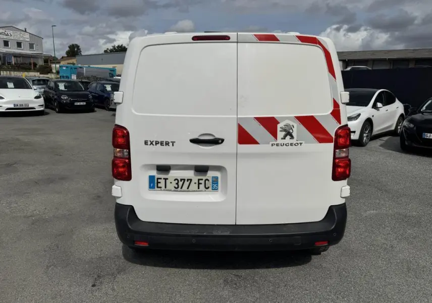 Vue arrière du Peugeot Expert Fourgon blanc avec bandes réfléchissantes rouges et blanches sur la porte droite.