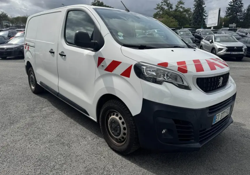 Vue 3/4 avant droit d’un Peugeot Expert Fourgon blanc avec bandes rouges diagonales sur capot et ailes, boucliers noirs.
