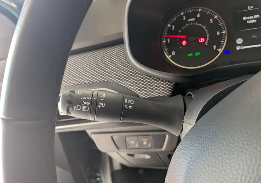 Gros plan sur la manette des feux à gauche du volant dans l’habitacle sombre du Dacia Jogger 2025.