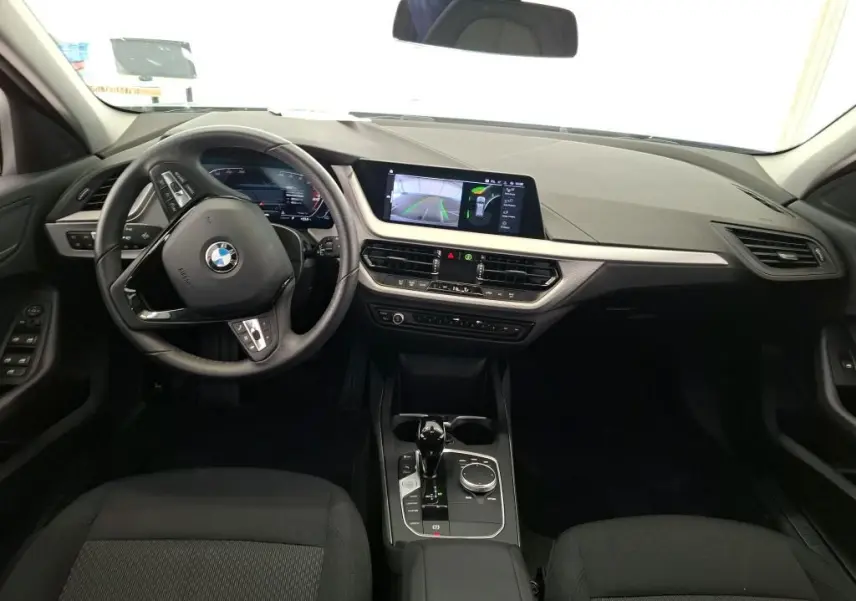 Vue intérieure du poste de conduite de la BMW Série 1 116d 2022 avec tableau de bord numérique et écran central tactile.