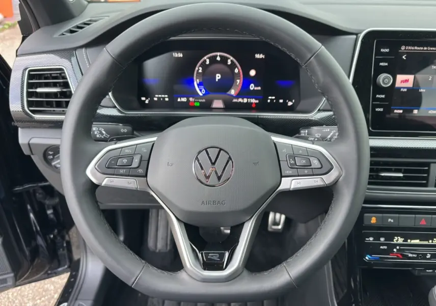 Vue rapprochée du volant cuir multifonctions noir du Volkswagen T-Cross TSI 116 DSG7 R-Line avec tableau de bord digital.