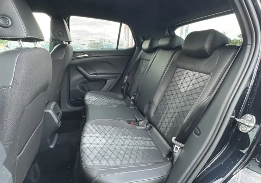 Vue intérieure côté droit montrant la banquette arrière en tissu noir avec motifs géométriques du Volkswagen T-Cross noir intense 2025.