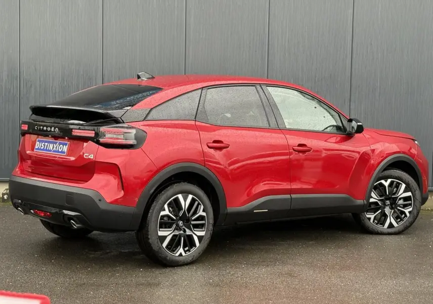 Vue 3/4 arrière droite d'une Citroën C4 rouge Elixir avec toit noir et jantes alliage 18 pouces diamantées.