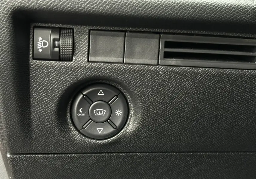 Détail du tableau de bord côté conducteur de la Citroën C4 Hybrid 2025 montrant les commandes de réglage des phares et du tableau de bord.