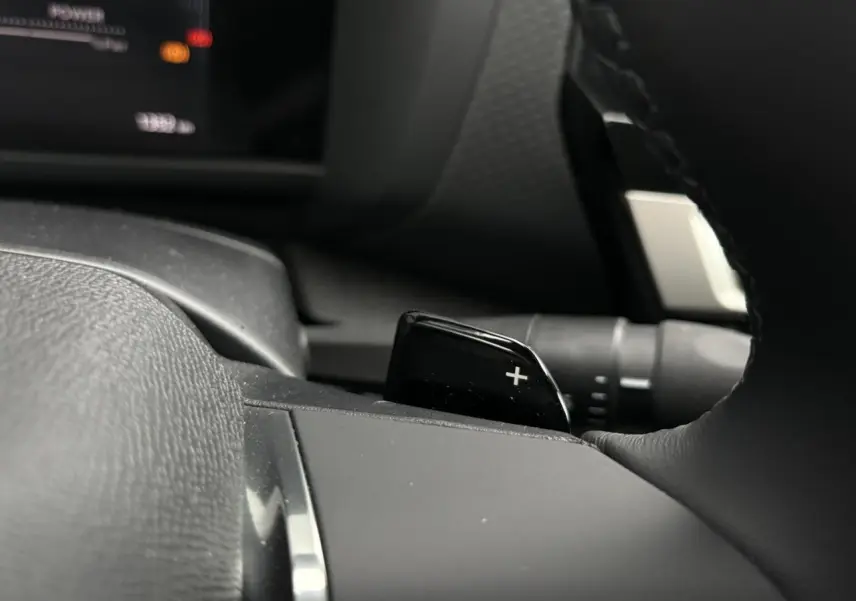 Gros plan sur la palette de changement de rapport droite au volant cuir noir de la Citroën C4 Hybrid 2025.
