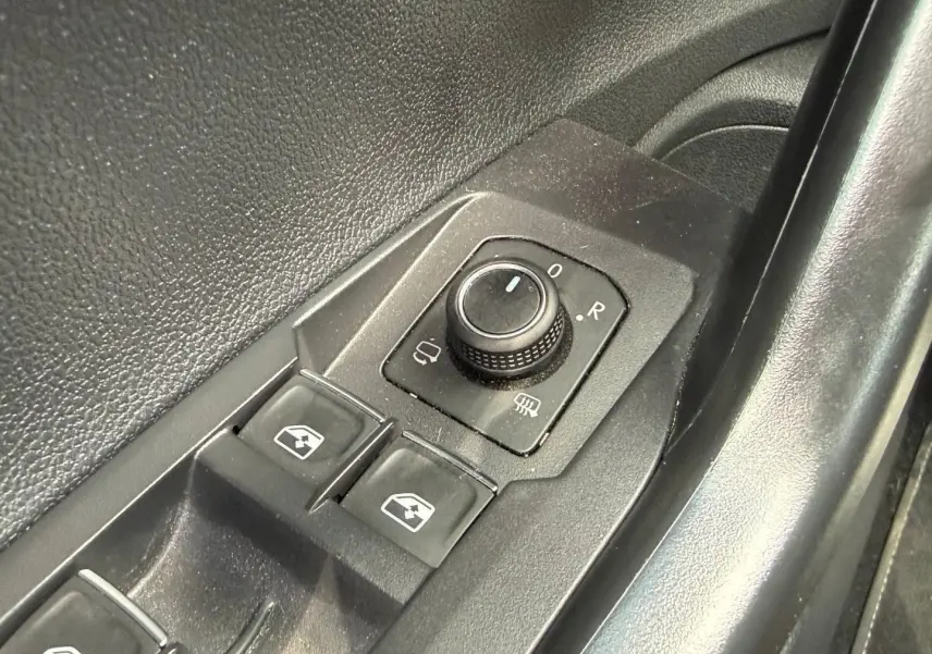 Gros plan sur les commandes de réglage des rétroviseurs et des vitres côté conducteur du Volkswagen Taigo gris 2025.