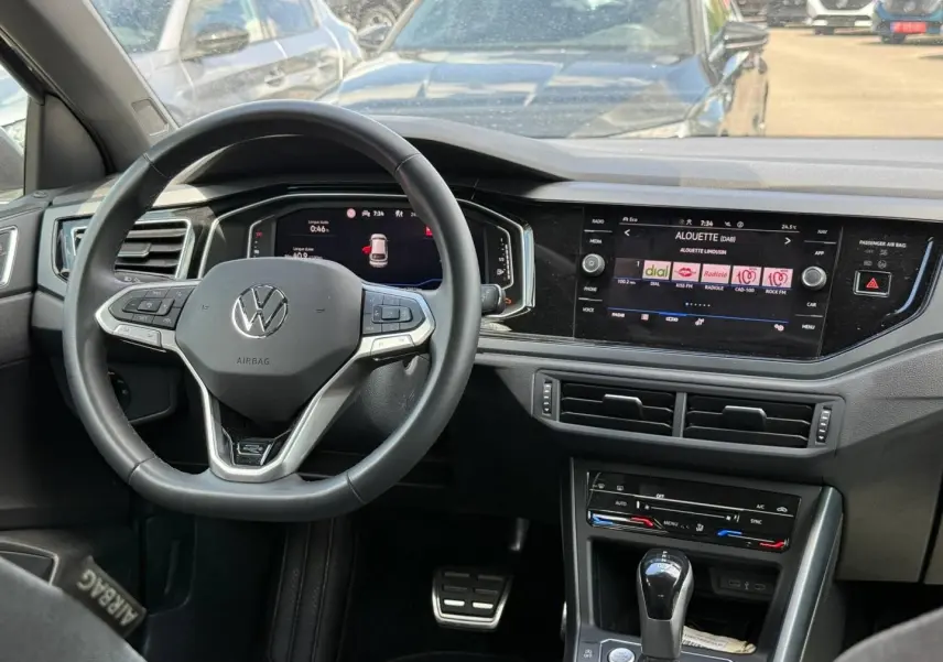 Vue intérieure du tableau de bord du Volkswagen Taigo gris 2025, volant cuir multifonction et écran tactile central.