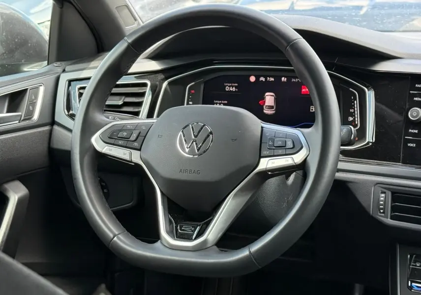 Vue rapprochée du volant cuir multifonction gris du Volkswagen Taigo 1.0 TSI R-Line avec tableau de bord digital.