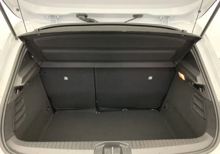Coffre ouvert vu de l'arrière d'une Renault Clio V blanc glacier, montrant un espace de chargement propre et bien agencé.