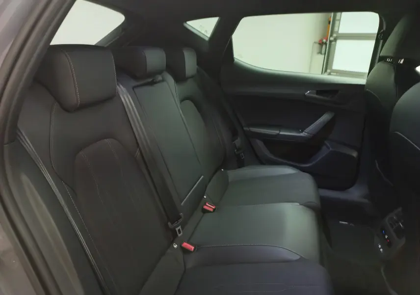 Vue intérieure des sièges arrière noirs avec surpiqûres claires d'une CUPRA Leon Phase 2, côté droit.
