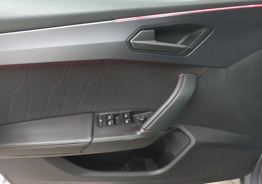 Vue rapprochée de la porte intérieure côté gauche de la CUPRA Leon Phase 2, avec garniture noire et surpiqûres orange.