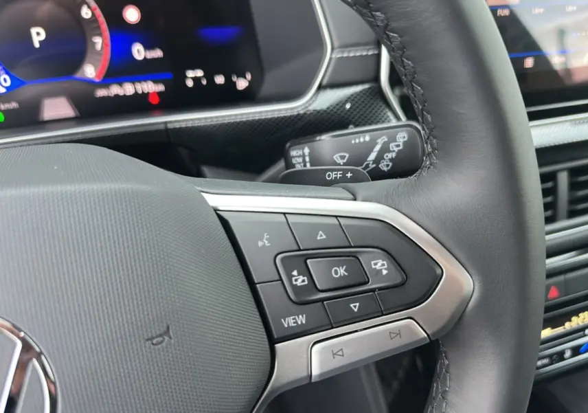 Gros plan sur le volant cuir multifonctions et le tableau de bord numérique du Volkswagen T-Cross noir intense 2025.