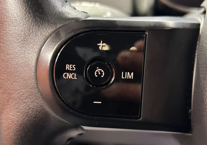 Gros plan sur les commandes de régulateur de vitesse au volant d’une MINI Countryman 2021 vert métallisé.