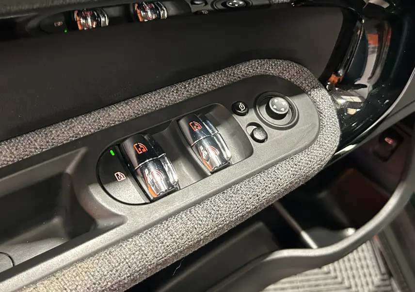Détail des commandes de lève-vitres et réglage des rétroviseurs sur la porte côté conducteur d’un MINI Countryman 2021.