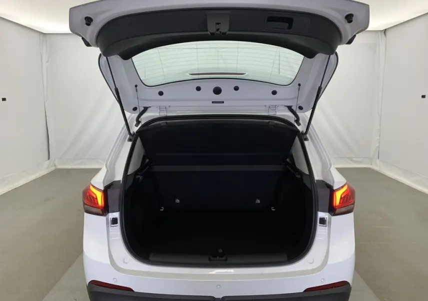 Vue arrière du MG ZS blanc Dover White 2026 avec coffre ouvert et feux arrière allumés dans un espace neutre.