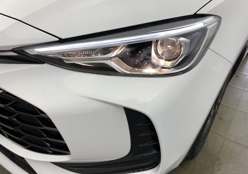 Gros plan sur le phare avant droit blanc Dover White du MG ZS 1.5L Hybrid+ 2026 avec calandre noire et détails LED.