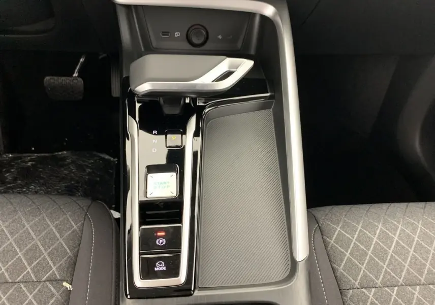 Vue plongeante sur la console centrale noire brillante du MG ZS blanc, avec levier de vitesse automatique et boutons start/stop.