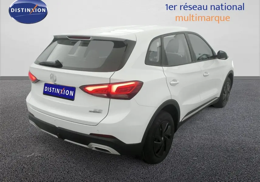 Vue 3/4 arrière droite du MG ZS blanc Dover White 2026 avec feux LED et badge Hybrid visible.