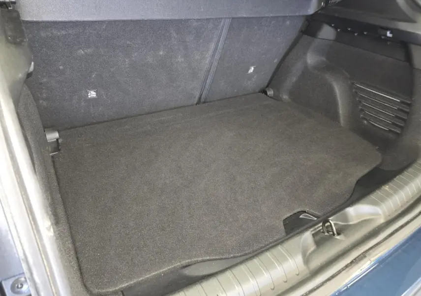 Coffre ouvert vu de dessus d'une FIAT 600 bleu, montrant le plancher de coffre noir et les sièges arrière rabattus.