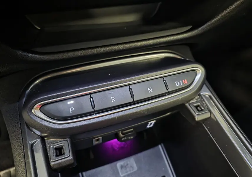 Gros plan sur la console centrale noire avec boutons de boîte auto et éclairage violet sous la prise USB, Fiat 600 Hybrid 2025.