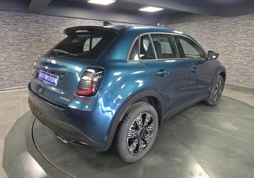 Vue 3/4 arrière droite d'une FIAT 600 hybride bleu métallisé avec jantes alliage et feux arrière LED dans un showroom.