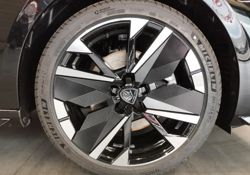 Gros plan sur la jante alliage 18" bi-tons noir et argent avec logo Peugeot sur une Peugeot 308 noir métallisé.