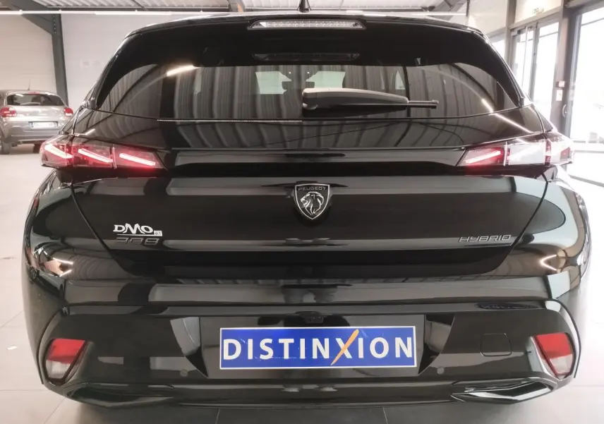 Vue arrière d'une Peugeot 308 hybride noire métallisée avec feux arrière LED en forme de griffes et logo central.