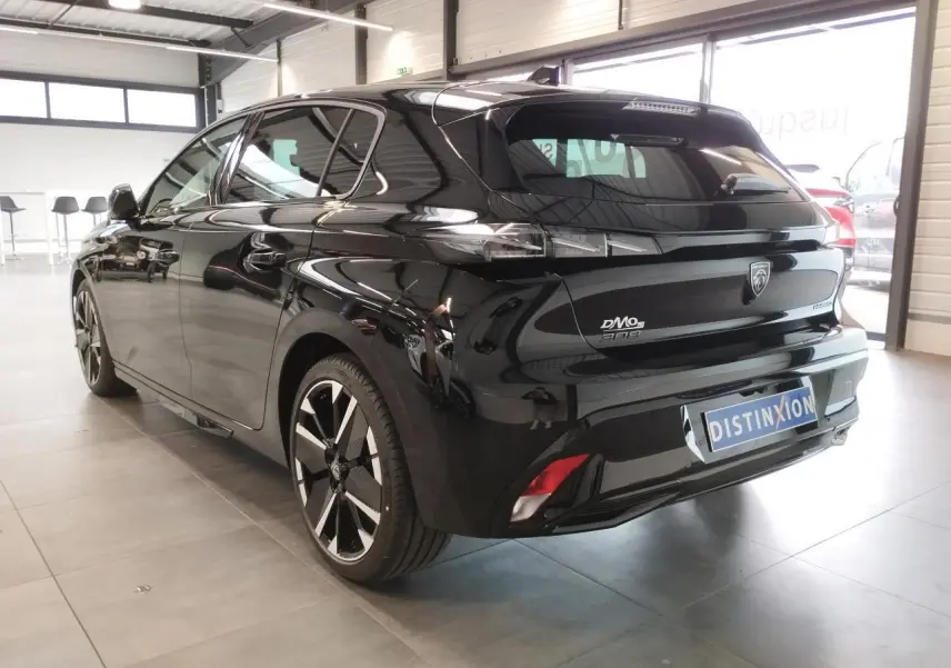 Peugeot 308 hybride noir métallisé vue 3/4 arrière droit en intérieur avec jantes bi-tons et feux LED griffés.