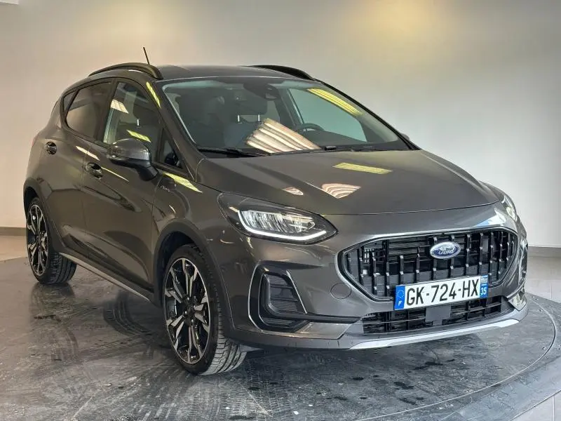 Vue 3/4 avant d'une Ford Fiesta 2022 gris Fashion Magnetic avec jantes alu 18 pouces et calandre noire distinctive.