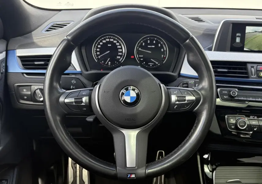 Vue frontale du volant cuir M et tableau de bord noir de la BMW X2 F39 avec écran multimédia et commandes intégrées.