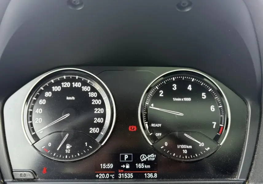 Tableau de bord de BMW X2 blanc, affichant compte-tours et compteur de vitesse avec écran digital central.